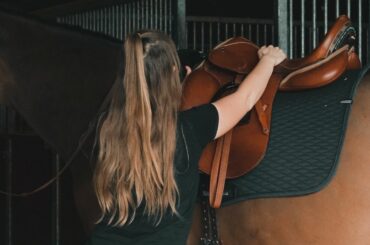 Ros fitting a Stubben Saddle to a bay horse
