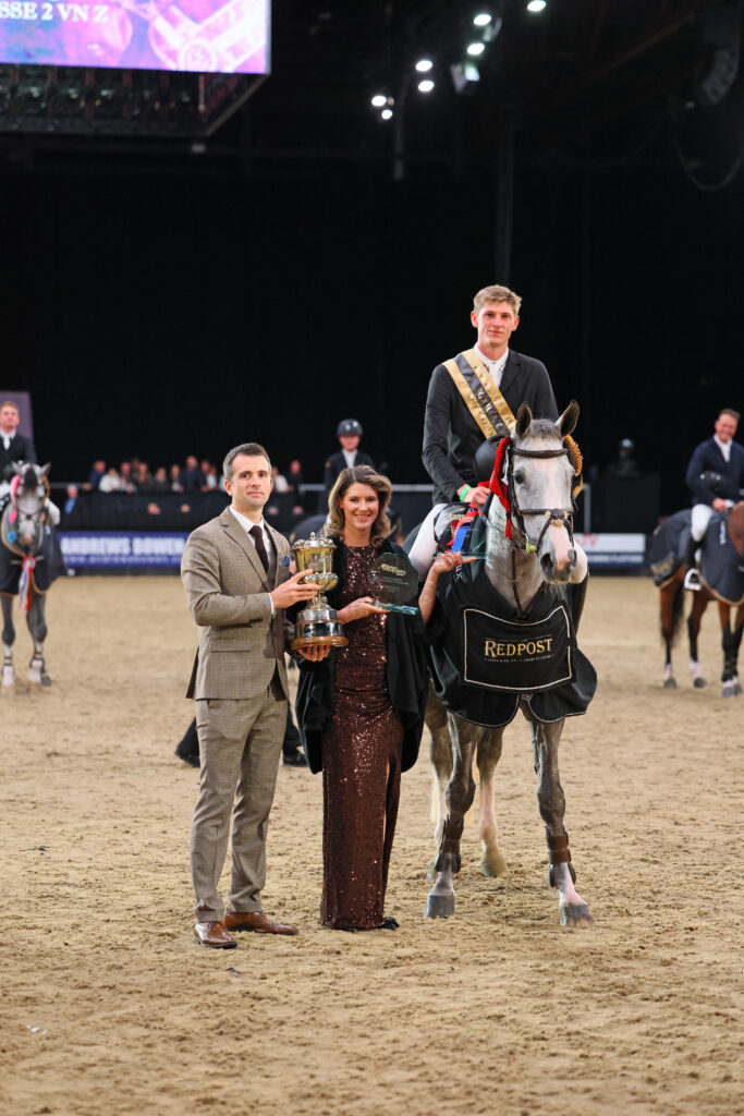 Ben and Claire Tuff presenting James Ingham with the winner's trophy for the Redpost Equestrian Senior Foxhunter Championship at HOYS, 2025.